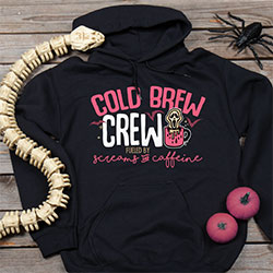 Your Name Crew, Fueled By Screams And Caffeine, next to a ghoul in a coffee mug and flanked by bats on a black hooded sweatshirt.