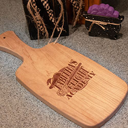 A cherry hardwood cheese board engraved with a Halloween design