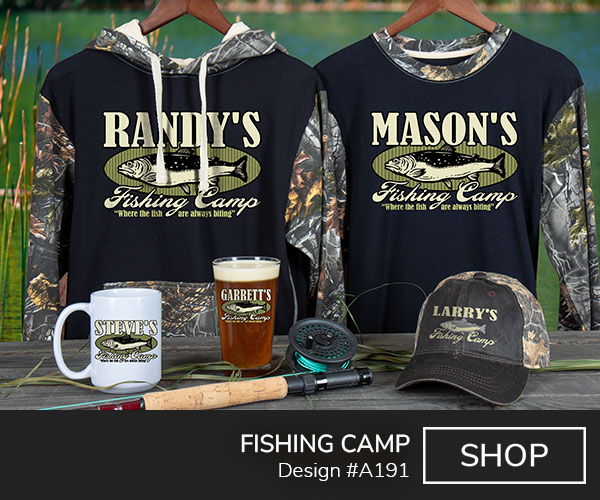 A191 | Fishing Camp - Your Name Fishing Camp, Where The Fish Are Always Biting, around a mounted fish trophy, on a 2 tone camo long sleeve tee, 2 tone camo hoodie, 2 tone camo hat, ceramic coffee mug, and a color printed pint glass.