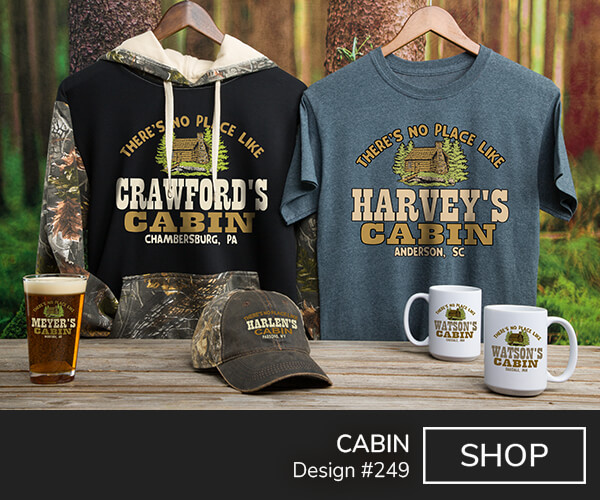 A249 | Cabin - There's No Place Like Your Name Cabin, Your Location, around a classic log cabin flanked by pine trees on a blue tee, 2 tone camo hoodie, 2 tone camo baseball hat, color printed pint glass, and ceramic coffee mugs.