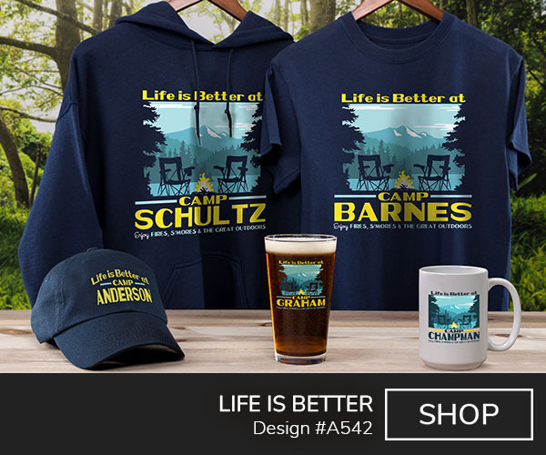 Design #A542 | Life Is Better - Life Is Better At Camp Your Name, Enjoy Fires, S'mores, and The Great Outdoors, around trees, camp chairs, and a campfire by a lake with a mountain in the distance, on a navy T shirt, color printed pint glass, ceramic coffee mug, and a navy hoodie.